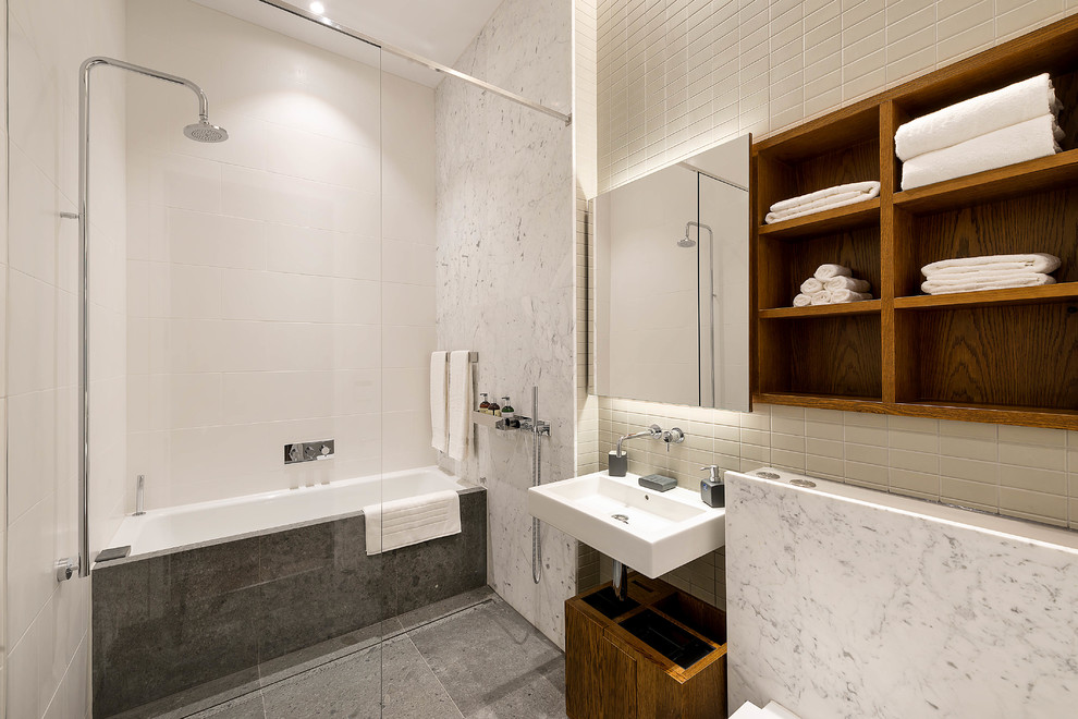 Design ideas for a contemporary master wet room bathroom in London with open cabinets, dark wood cabinets, an alcove tub, white tile, white walls, a wall-mount sink and grey floor.