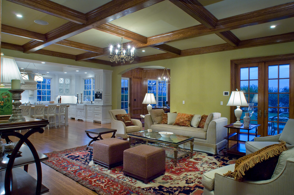 This is an example of a large traditional open concept living room in New York with a home bar, yellow walls, medium hardwood floors, a standard fireplace, a stone fireplace surround and no tv.
