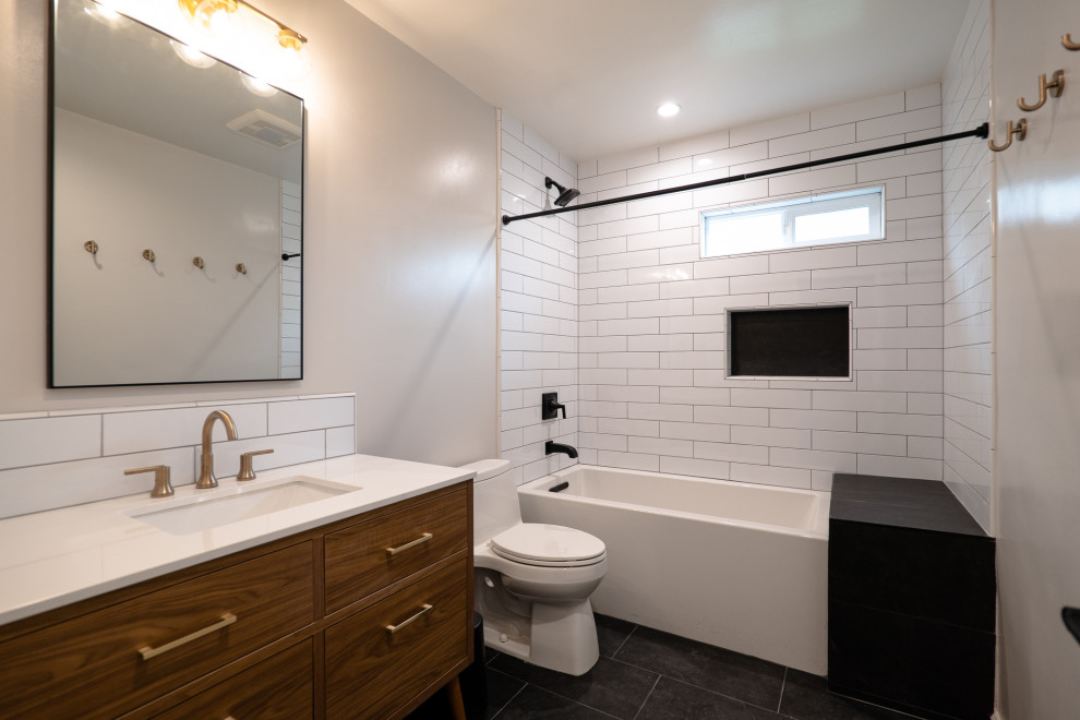 Exempel på ett mellanstort klassiskt vit vitt en-suite badrum, med möbel-liknande, skåp i mellenmörkt trä, ett undermonterat badkar, en dusch/badkar-kombination, en toalettstol med hel cisternkåpa, vit kakel, tunnelbanekakel, vita väggar, klinkergolv i porslin, ett nedsänkt handfat, bänkskiva i kvartsit, svart golv och dusch med duschdraperi