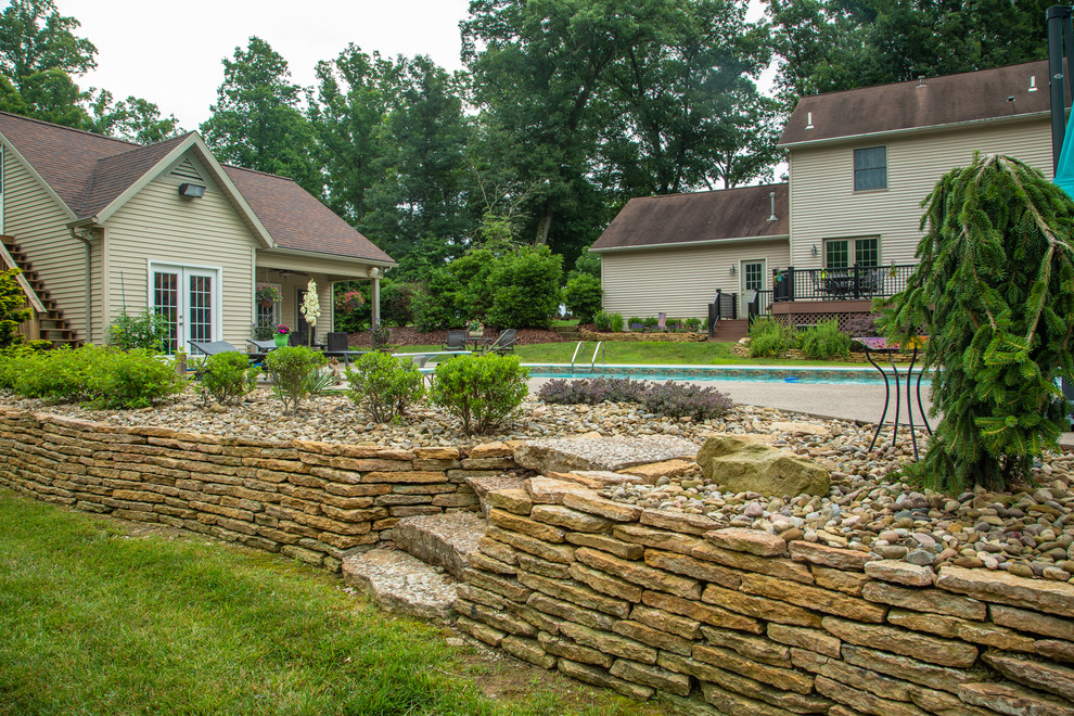 Photo of a mid-sized transitional drought-tolerant and full sun backyard stone retaining wall landscape for summer.