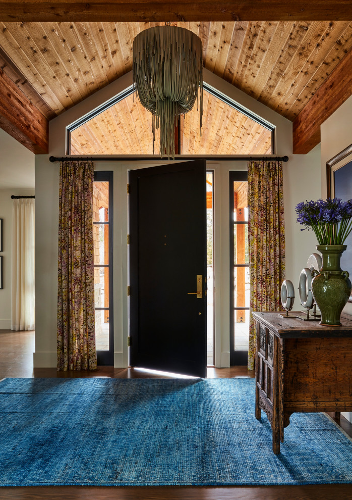 Klassisches Foyer mit beiger Wandfarbe, Einzeltür, schwarzer Haustür, gewölbter Decke, Holzwänden, braunem Boden und braunem Holzboden in Denver