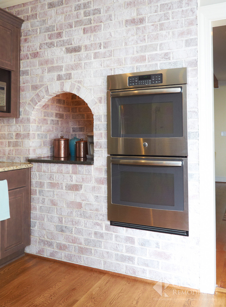 Transitional light wood floor eat-in kitchen photo with shaker cabinets, dark wood cabinets, granite countertops, beige backsplash, glass tile backsplash, stainless steel appliances and an island