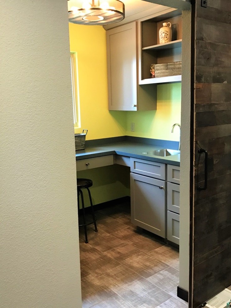 Dedicated laundry room - mid-sized transitional vinyl floor dedicated laundry room idea with an undermount sink, shaker cabinets, gray cabinets, laminate countertops, yellow walls and a stacked washer/dryer