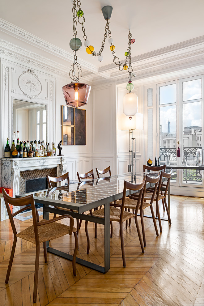 Inspiration for a large transitional open plan dining in Paris with white walls, light hardwood floors, a stone fireplace surround and a standard fireplace.
