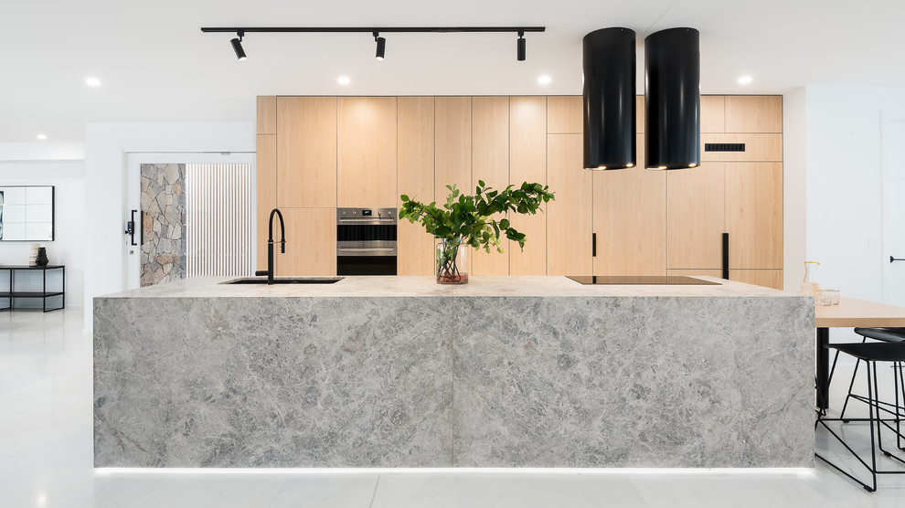 Mid-sized contemporary galley eat-in kitchen in Brisbane with an undermount sink, light wood cabinets, limestone benchtops, grey splashback, marble floors, with island, white floor, grey benchtop, flat-panel cabinets and stainless steel appliances.