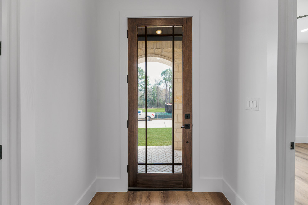 Aménagement d'une entrée classique avec parquet clair, une porte simple, une porte en bois foncé et un sol marron.