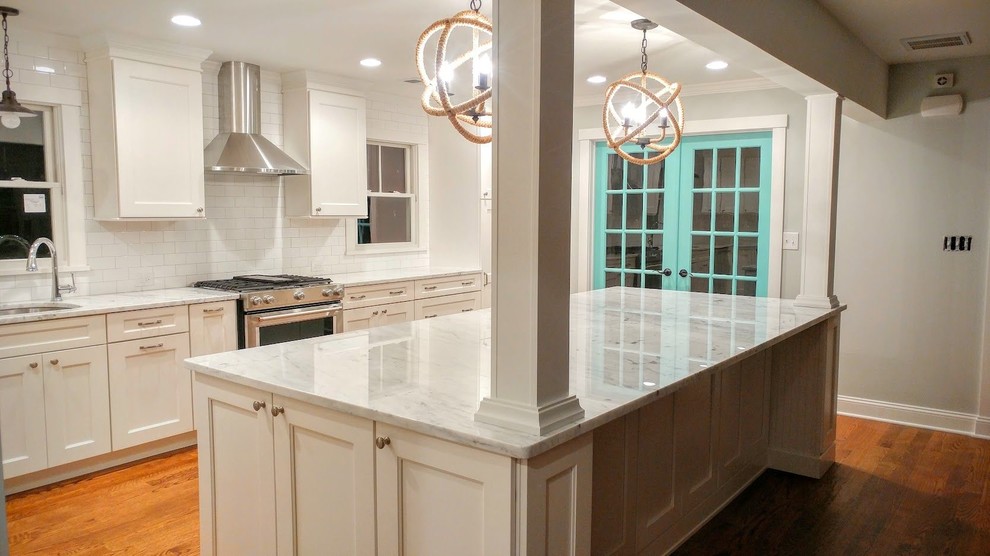 Example of a large transitional l-shaped light wood floor and beige floor open concept kitchen design with an undermount sink, beaded inset cabinets, white cabinets, marble countertops, white backsplash, subway tile backsplash, stainless steel appliances, an island and gray countertops
