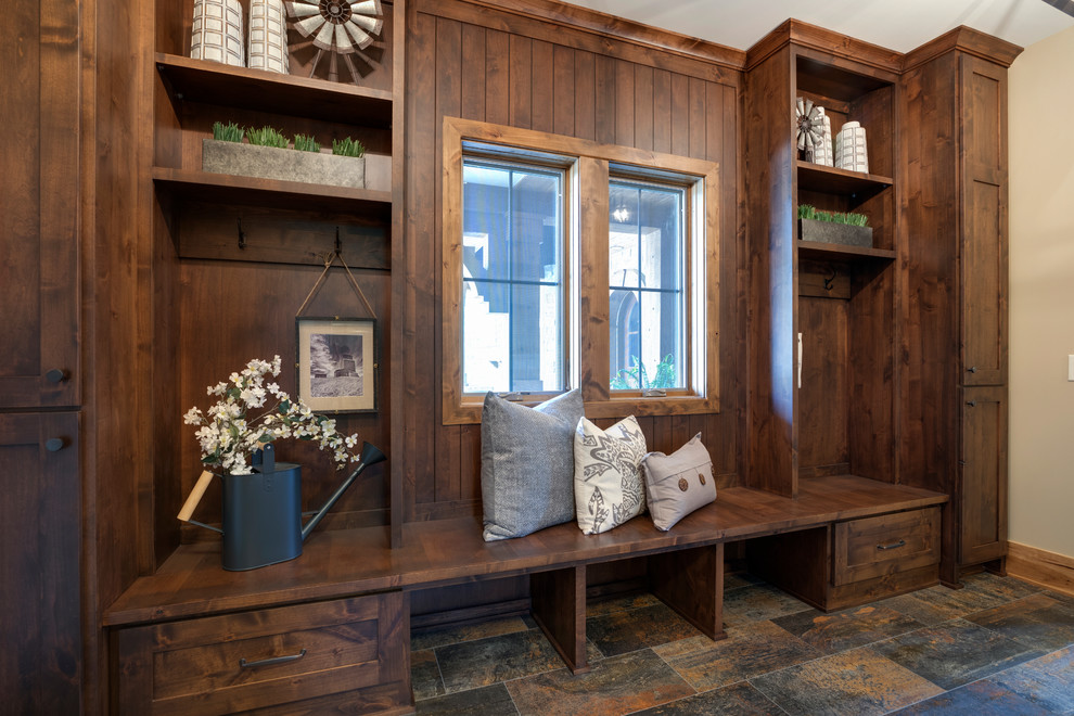 This is an example of a large country mudroom in Minneapolis with beige walls, ceramic floors, a medium wood front door and brown floor.