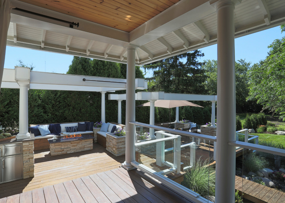 Example of a huge transitional backyard deck design in Chicago with a pergola and a fire pit