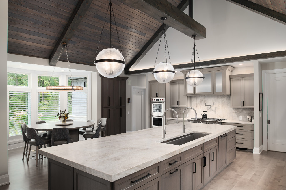 Large transitional galley bamboo floor, beige floor and vaulted ceiling eat-in kitchen photo in Chicago with an integrated sink, gray cabinets, marble countertops, beige backsplash, granite backsplash, stainless steel appliances, an island and beige countertops