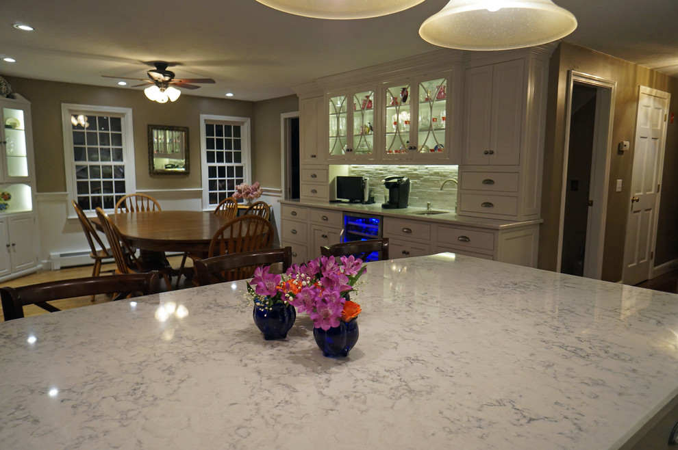 Photo of a large transitional l-shaped eat-in kitchen in Boston with an undermount sink, beaded inset cabinets, white cabinets, quartz benchtops, white splashback, stone tile splashback, stainless steel appliances, dark hardwood floors and with island.