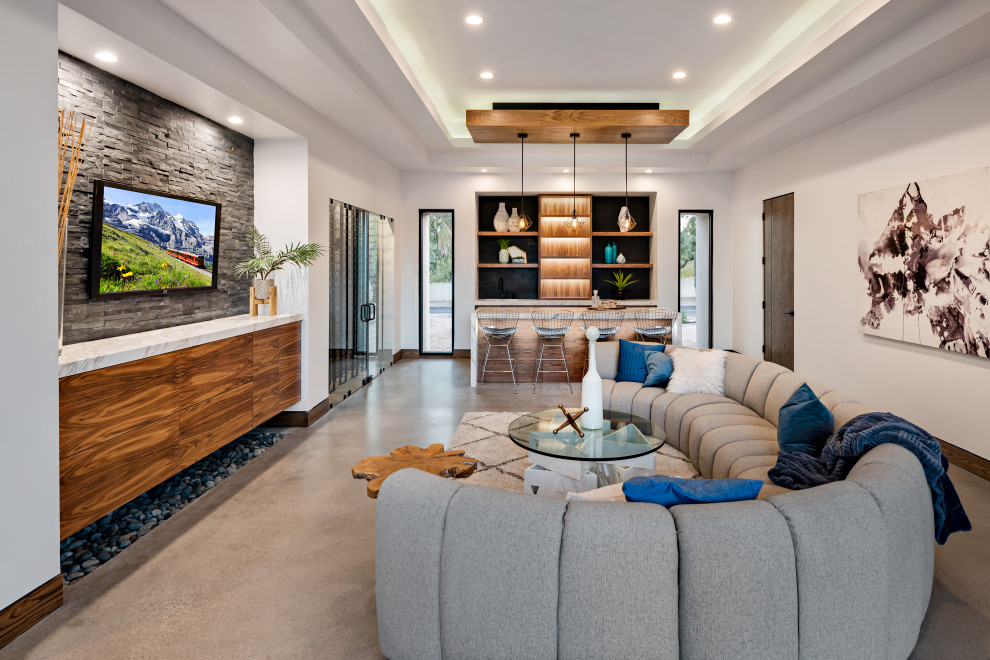 This is an example of a contemporary family room in Phoenix with a home bar, white walls, concrete floors, no fireplace, a wall-mounted tv, grey floor and recessed.