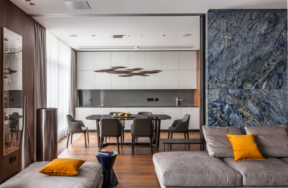 This is an example of a contemporary open plan kitchen in Moscow with flat-panel cabinets, white cabinets, grey splashback, medium hardwood floors, no island and brown floor.