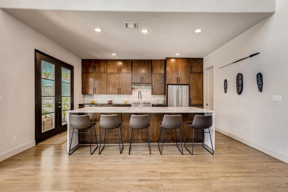 Inspiration for a large transitional single-wall eat-in kitchen in Houston with a farmhouse sink, raised-panel cabinets, brown cabinets, quartzite benchtops, beige splashback, ceramic splashback, stainless steel appliances, plywood floors, with island, beige floor, black benchtop and coffered.