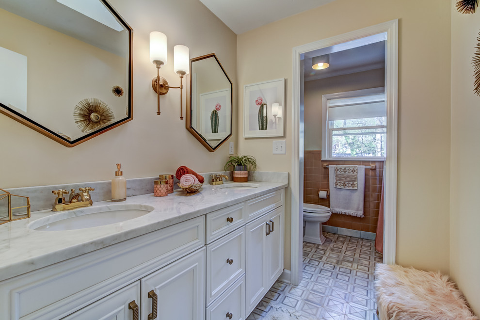 Photo of a mid-sized transitional master bathroom in Atlanta with recessed-panel cabinets, white cabinets, an alcove shower, a two-piece toilet, multi-coloured walls, cement tiles, an undermount sink, marble benchtops, white floor and a shower curtain.