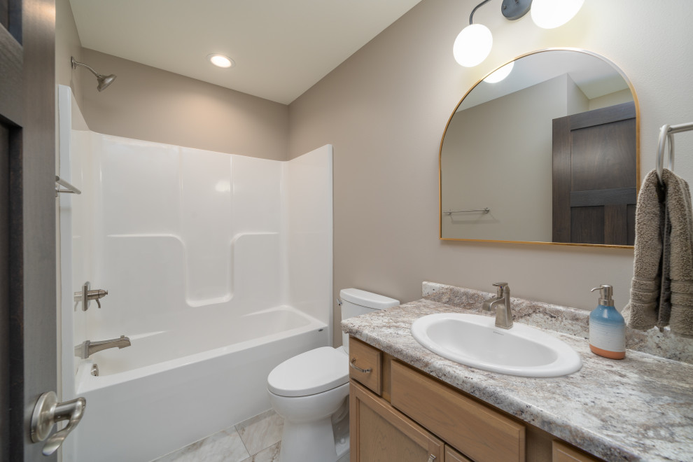 Transitional kids' vinyl floor, white floor and single-sink alcove bathtub photo with shaker cabinets, light wood cabinets, a two-piece toilet, gray walls, a drop-in sink, laminate countertops, gray countertops and a built-in vanity