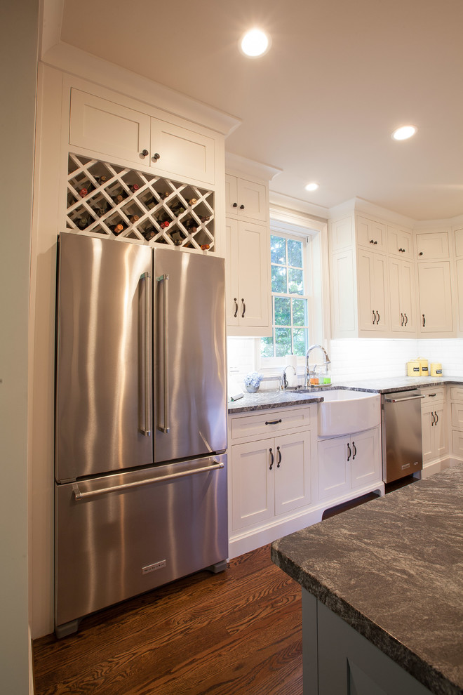 Large transitional l-shaped eat-in kitchen in Atlanta with a farmhouse sink, shaker cabinets, white cabinets, granite benchtops, white splashback, ceramic splashback, stainless steel appliances, dark hardwood floors and with island.