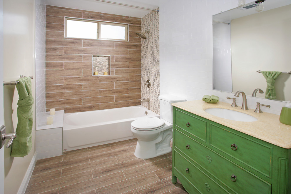 This is an example of a small arts and crafts 3/4 bathroom in Los Angeles with a drop-in sink, furniture-like cabinets, green cabinets, granite benchtops, an alcove tub, a shower/bathtub combo, a two-piece toilet, brown tile, ceramic tile, white walls and ceramic floors.