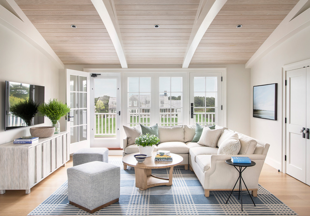 This is an example of a beach style open concept family room in Providence with white walls, light hardwood floors, a wall-mounted tv, beige floor, vaulted and wood.