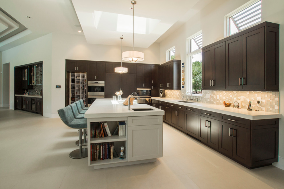 Example of a large transitional l-shaped kitchen pantry design in Miami with shaker cabinets, dark wood cabinets, quartz countertops, beige backsplash, paneled appliances and an island