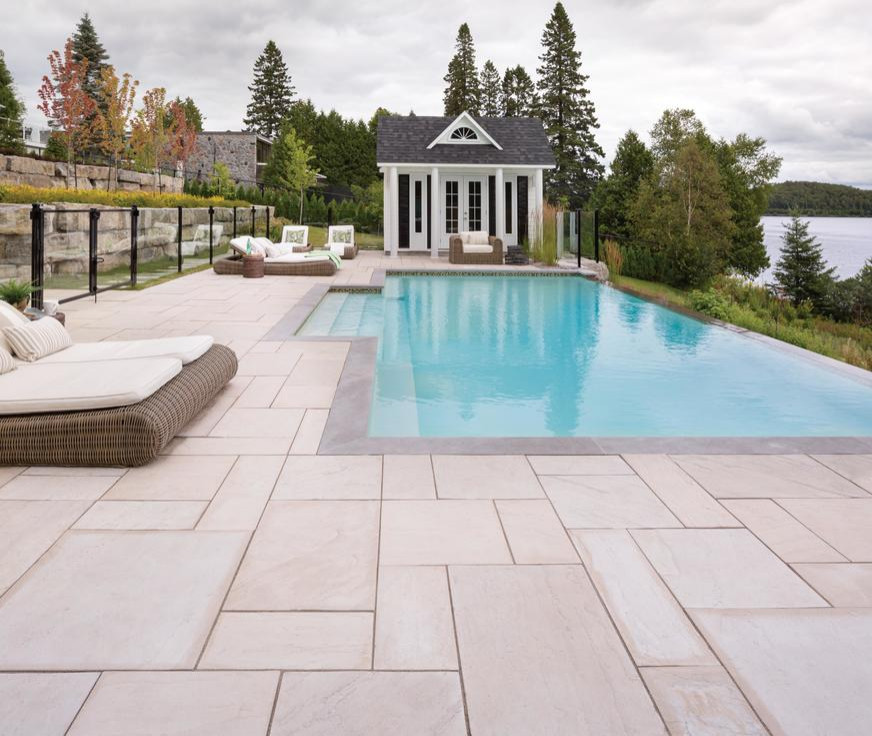 Foto de piscina infinita clásica de tamaño medio tipo riñón en patio trasero con paisajismo de piscina y losas de hormigón