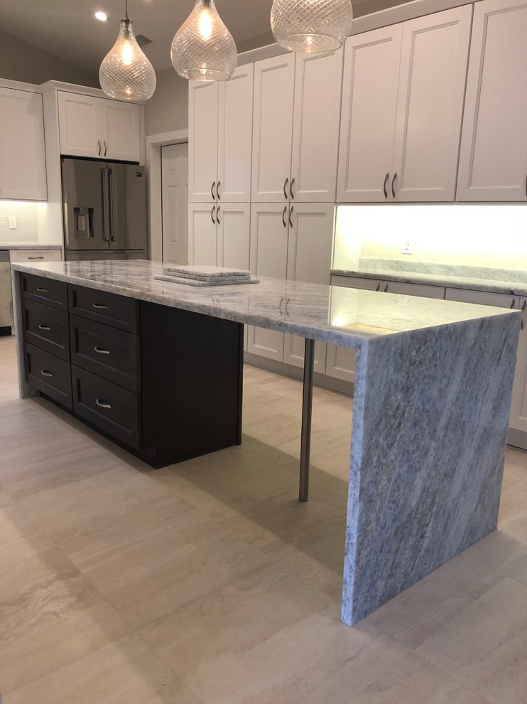 Inspiration for a mid-sized transitional u-shaped beige floor kitchen remodel in Miami with an undermount sink, recessed-panel cabinets, white cabinets, gray backsplash, glass tile backsplash, stainless steel appliances, an island and gray countertops