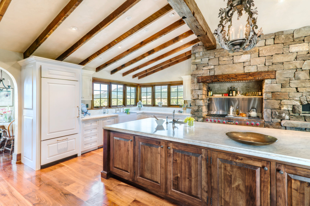 Large country l-shaped kitchen in Other with a farmhouse sink, raised-panel cabinets, white cabinets, quartzite benchtops, panelled appliances, medium hardwood floors and with island.