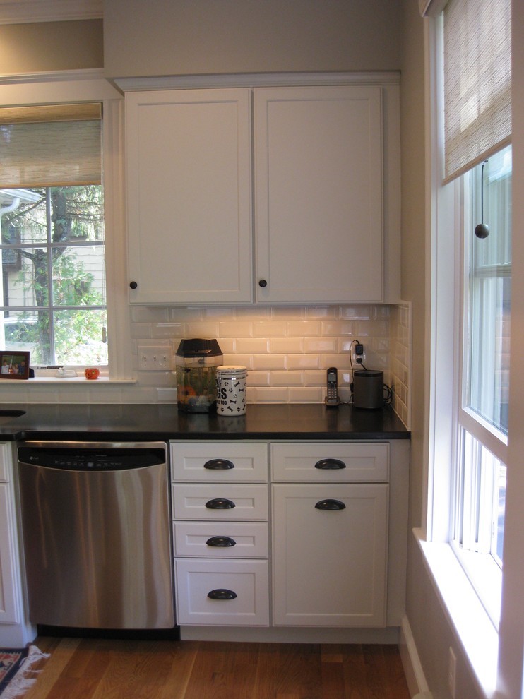Eat-in kitchen - transitional l-shaped medium tone wood floor eat-in kitchen idea in Boston with an undermount sink, shaker cabinets, white cabinets, granite countertops, white backsplash, ceramic backsplash, stainless steel appliances, an island and black countertops