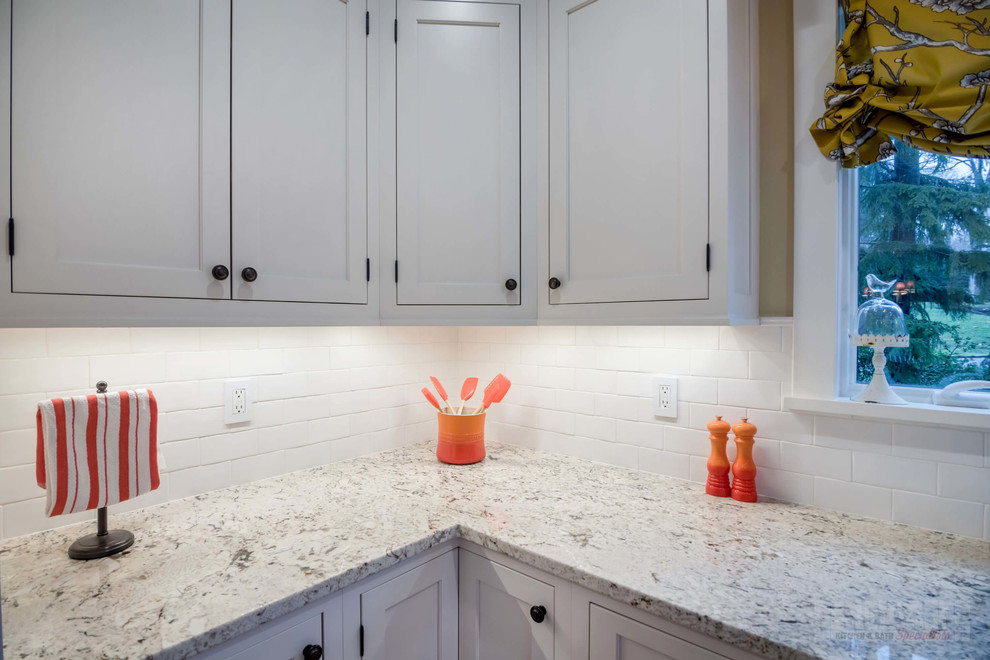 Mid-sized l-shaped eat-in kitchen in New York with a farmhouse sink, recessed-panel cabinets, white cabinets, granite benchtops, white splashback, stainless steel appliances, plywood floors and with island.