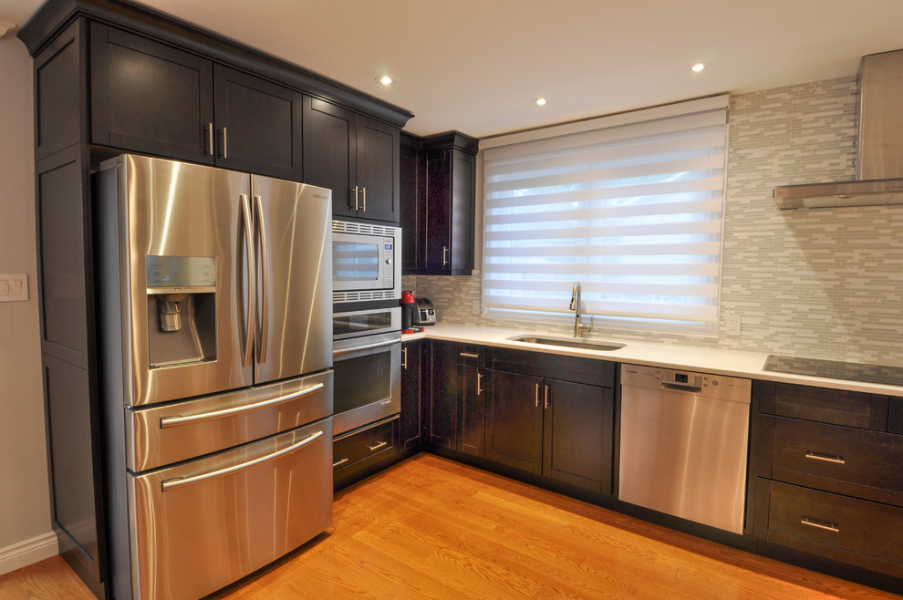 Inspiration for a large transitional galley light wood floor and brown floor enclosed kitchen remodel in Toronto with a single-bowl sink, shaker cabinets, dark wood cabinets, quartzite countertops, beige backsplash, stone tile backsplash, stainless steel appliances and no island