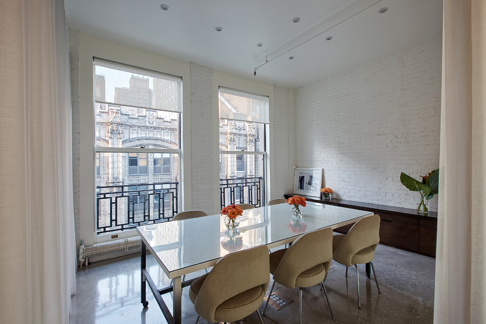 Photo of an industrial separate dining room in New York with white walls.