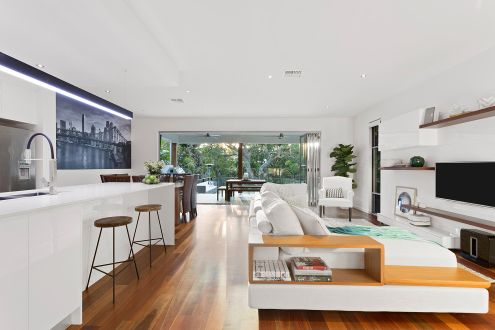 Photo of a contemporary open concept living room in Brisbane with white walls, dark hardwood floors, a wall-mounted tv and brown floor.