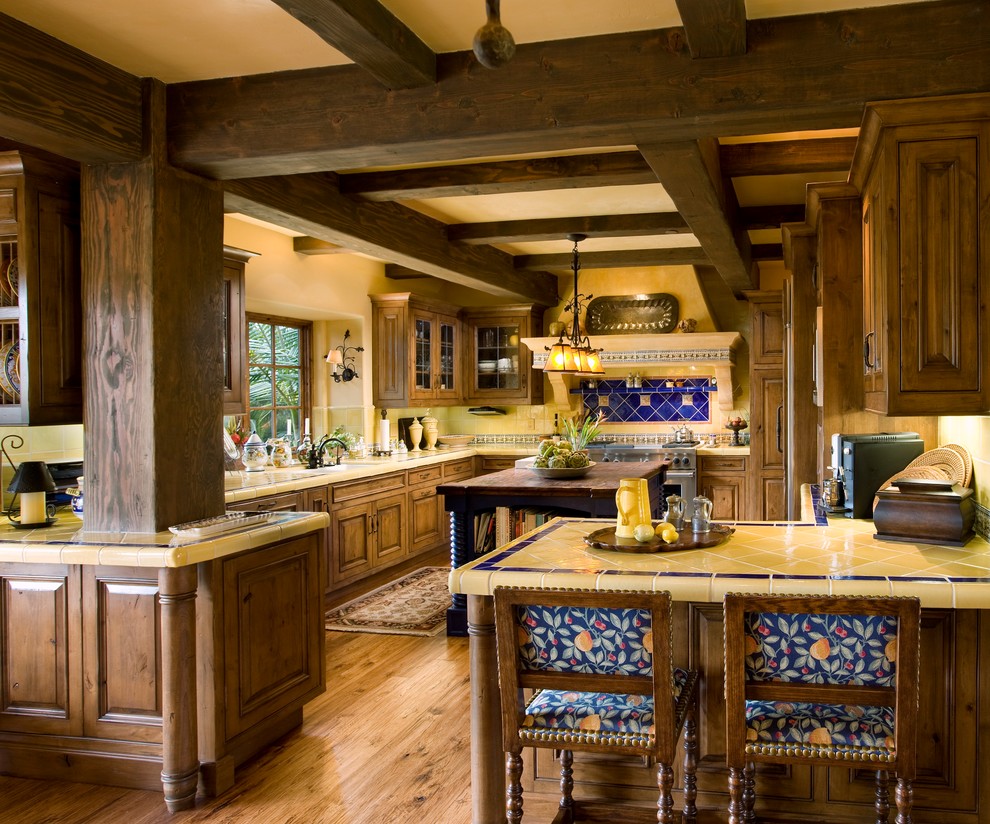 Inspiration for a mediterranean kitchen in Santa Barbara with medium wood cabinets, tile benchtops, blue splashback and yellow benchtop.