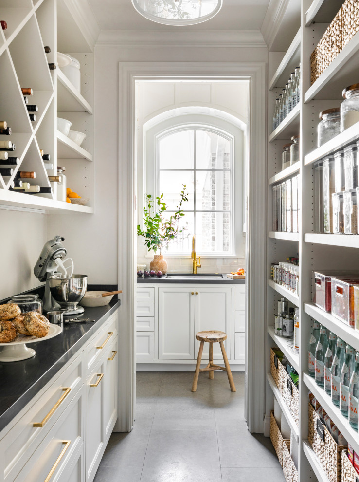 Imagen de cocina clásica con despensa, puertas de armario blancas, encimera de cuarcita, una isla y encimeras negras