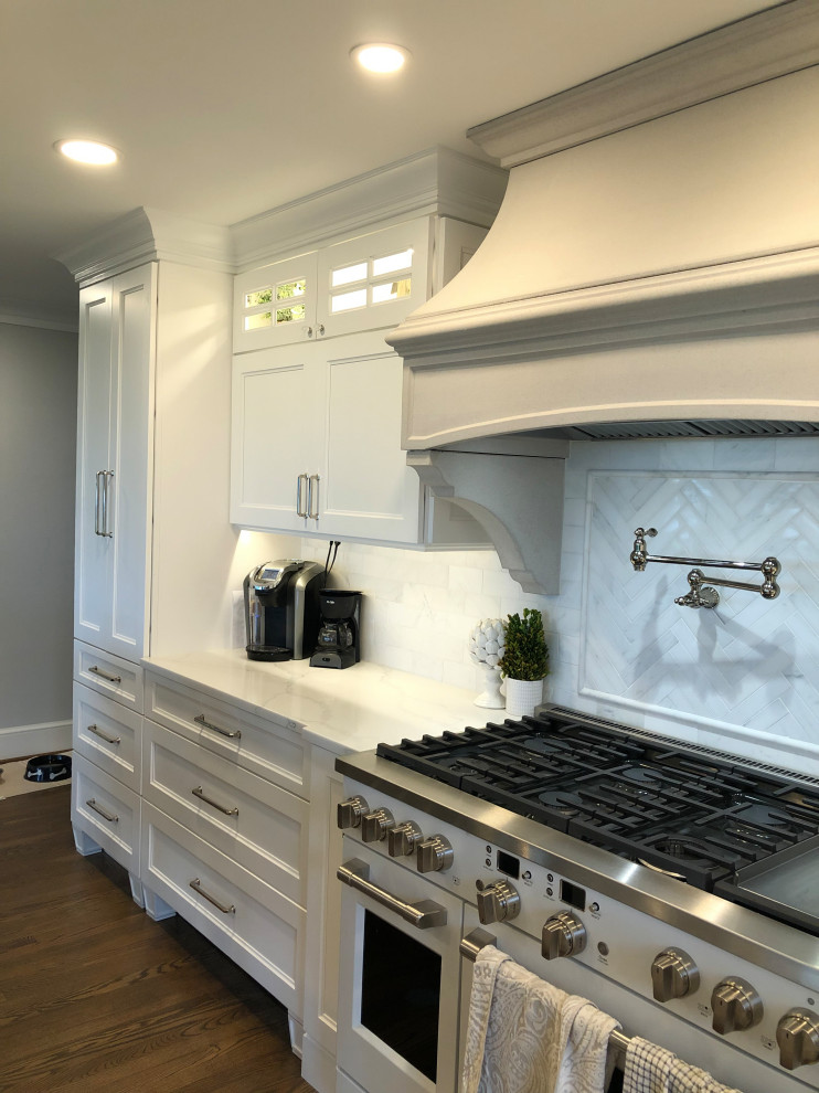 Eat-in kitchen - large transitional l-shaped medium tone wood floor and brown floor eat-in kitchen idea in Baltimore with a farmhouse sink, shaker cabinets, white cabinets, quartz countertops, white backsplash, subway tile backsplash, stainless steel appliances, an island and white countertops