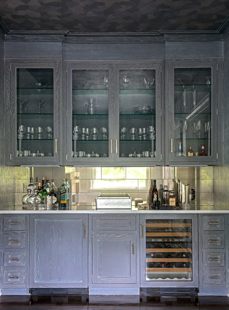Mid-sized transitional single-wall wet bar in New York with no sink, glass-front cabinets, grey cabinets, solid surface benchtops, multi-coloured splashback, dark hardwood floors, brown floor and mirror splashback.