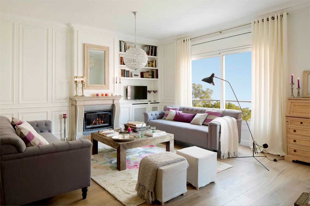 Inspiration for a mid-sized scandinavian enclosed living room in Barcelona with a library, white walls, medium hardwood floors, a standard fireplace and a freestanding tv.
