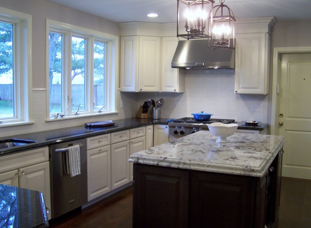 Large transitional u-shaped dark wood floor kitchen photo in St Louis with a farmhouse sink, recessed-panel cabinets, white cabinets, granite countertops, beige backsplash, ceramic backsplash, stainless steel appliances and an island