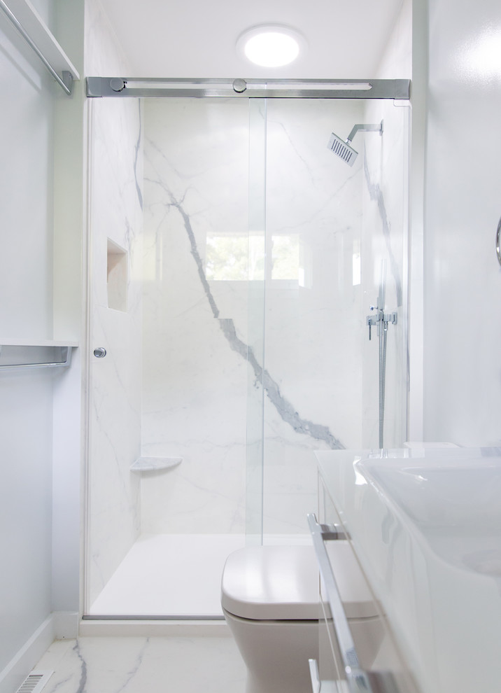 Inspiration for a small contemporary master bathroom in New York with white cabinets, an alcove shower, a one-piece toilet, white tile, porcelain tile, blue walls, porcelain floors, a wall-mount sink, glass benchtops, white floor, a sliding shower screen and white benchtops.