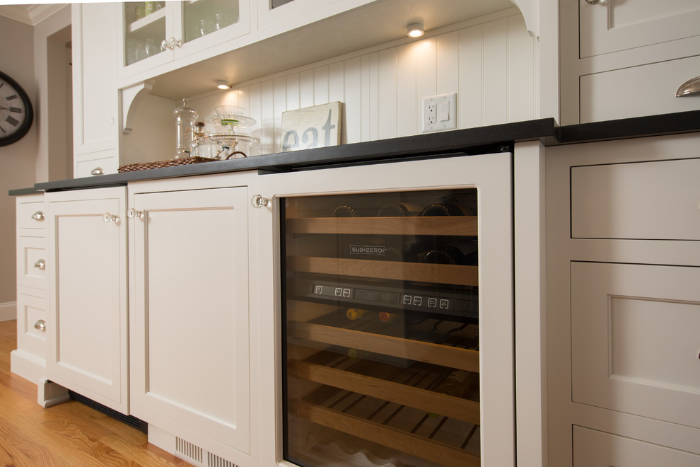 Example of a transitional medium tone wood floor home design design in Boston with a farmhouse sink, recessed-panel cabinets, white cabinets, granite countertops, white backsplash, subway tile backsplash, stainless steel appliances and two islands