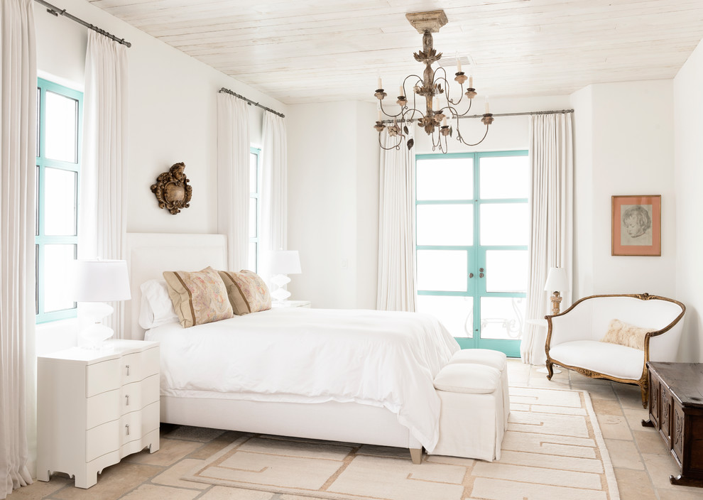 Mid-sized mediterranean guest bedroom in Houston with white walls, no fireplace and limestone floors.