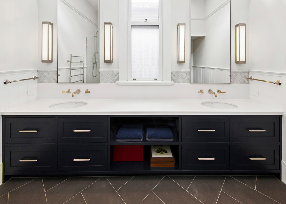 На фото: большая детская ванная комната с фасадами в стиле шейкер, синими фасадами, душем в нише, унитазом-моноблоком, серой плиткой, мраморной плиткой, белыми стенами, полом из керамической плитки, врезной раковиной, столешницей из искусственного кварца, серым полом, душем с распашными дверями, белой столешницей, тумбой под две раковины, встроенной тумбой и панелями на части стены