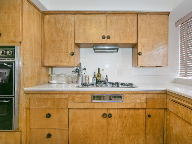 Photo of a mid-sized midcentury u-shaped eat-in kitchen with flat-panel cabinets, light wood cabinets, laminate benchtops, stainless steel appliances, ceramic floors and with island.