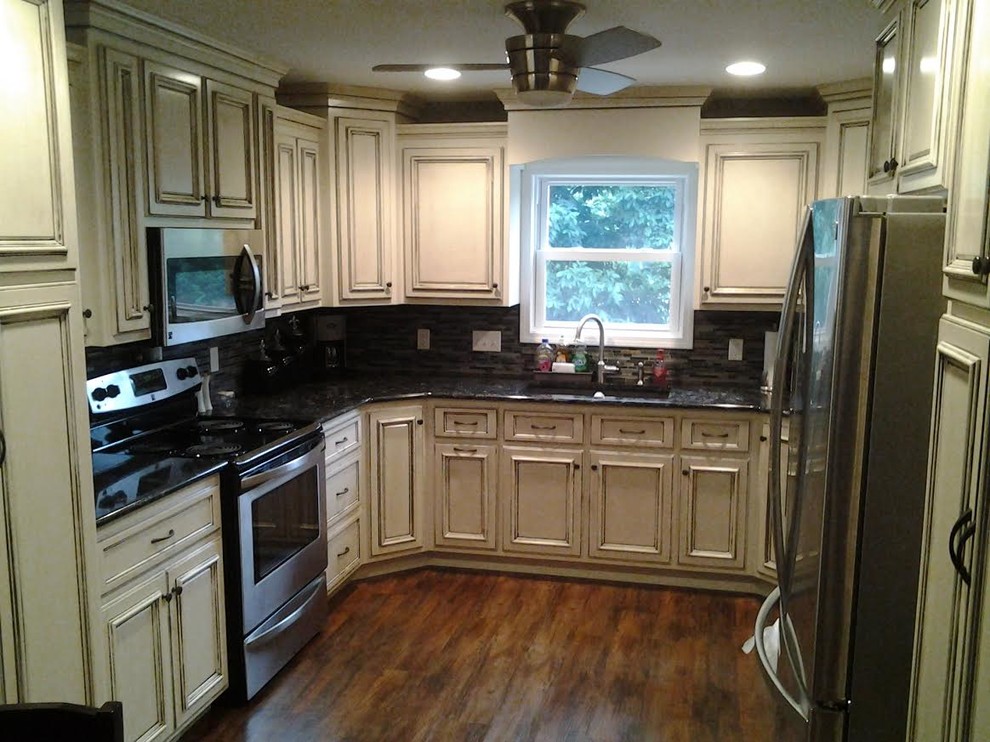 Inspiration for a mid-sized transitional u-shaped dark wood floor and brown floor enclosed kitchen remodel with an undermount sink, recessed-panel cabinets, distressed cabinets, granite countertops, multicolored backsplash, glass tile backsplash, stainless steel appliances and no island