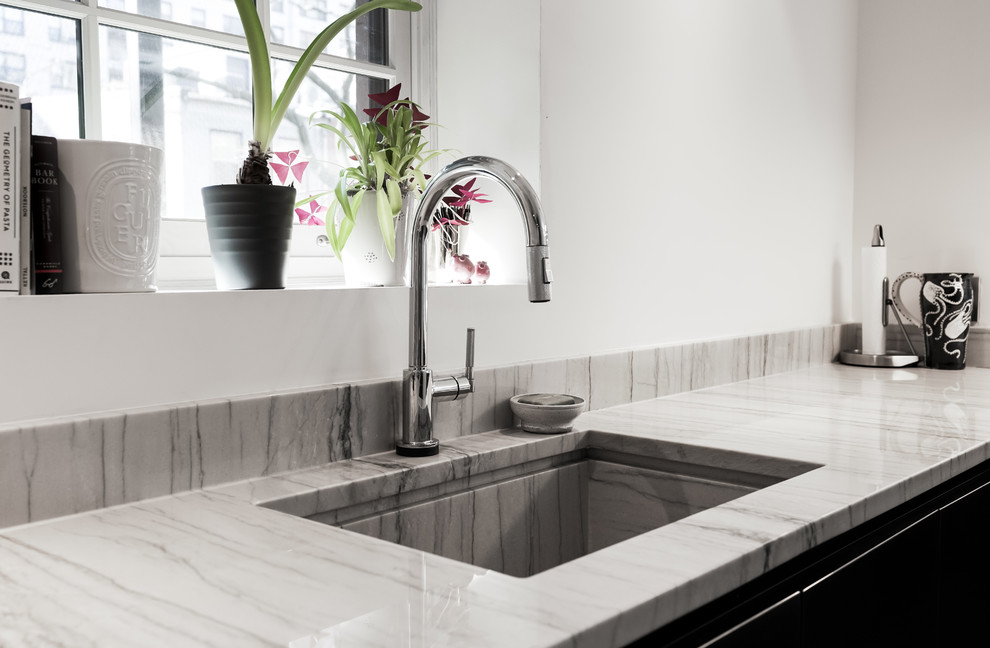 Design ideas for a modern u-shaped eat-in kitchen in New York with an integrated sink, beige splashback, stone slab splashback, stainless steel appliances and beige benchtop.