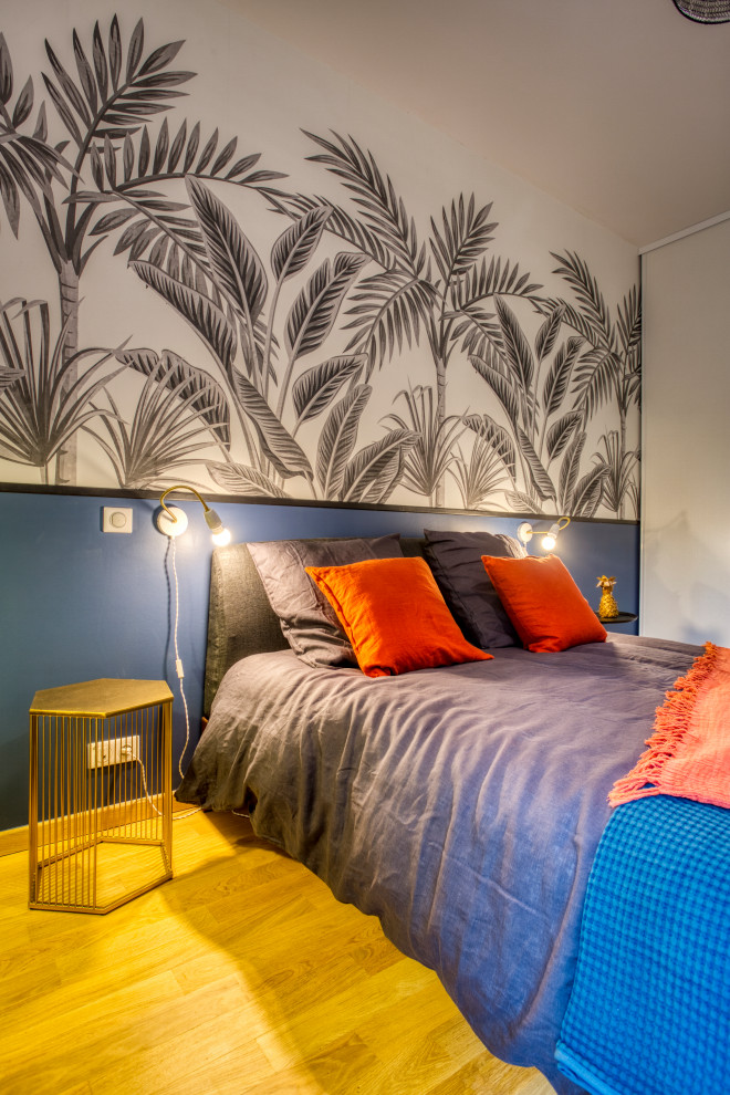 Mittelgroßes Modernes Hauptschlafzimmer mit blauer Wandfarbe, hellem Holzboden, braunem Boden und Tapetenwänden in Paris