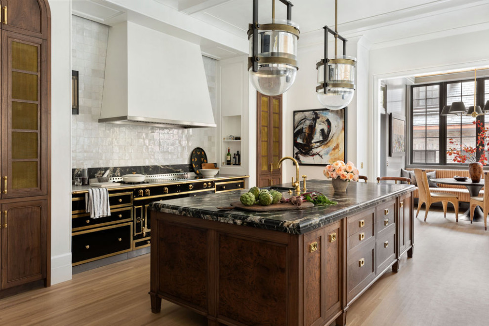 Transitional galley light wood floor, beige floor and exposed beam kitchen photo in Chicago with an undermount sink, shaker cabinets, dark wood cabinets, white backsplash, black appliances, an island and black countertops