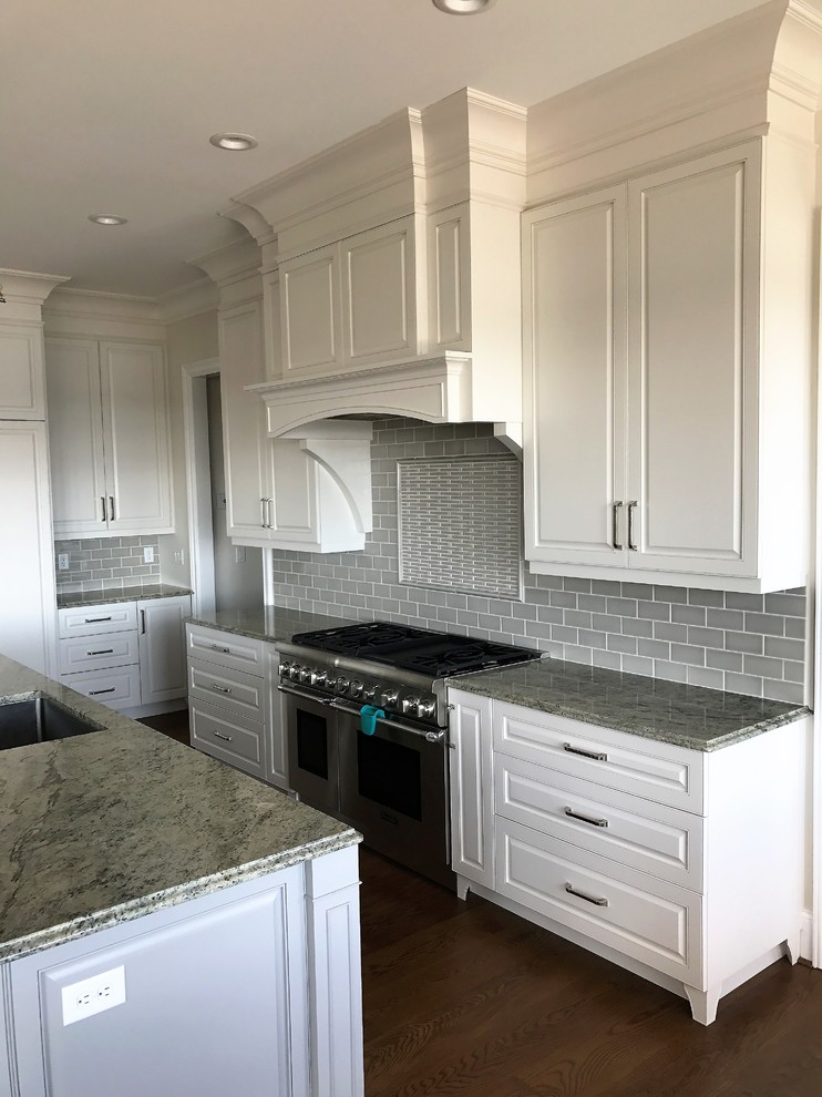 Inspiration for a large traditional l-shaped eat-in kitchen in Other with a single-bowl sink, raised-panel cabinets, white cabinets, quartz benchtops, grey splashback, porcelain splashback, stainless steel appliances, dark hardwood floors and with island.
