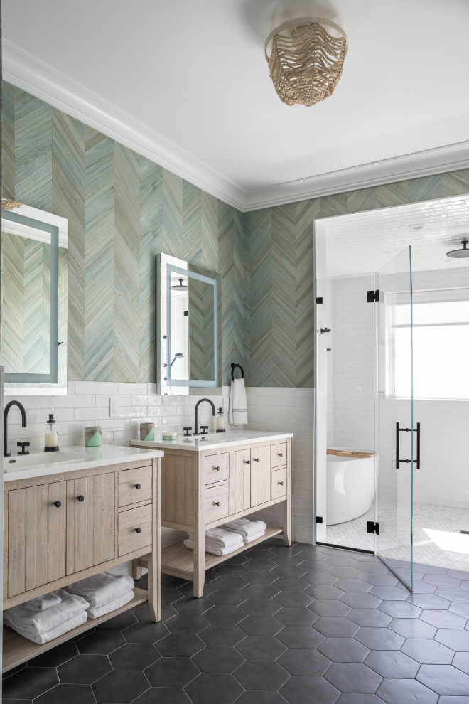 Inspiration for a coastal wet room bathroom in New York with flat-panel cabinets, light wood cabinets, a freestanding bath, white tiles, green walls, a submerged sink, black floors, white worktops, double sinks, a freestanding vanity unit and wallpapered walls.