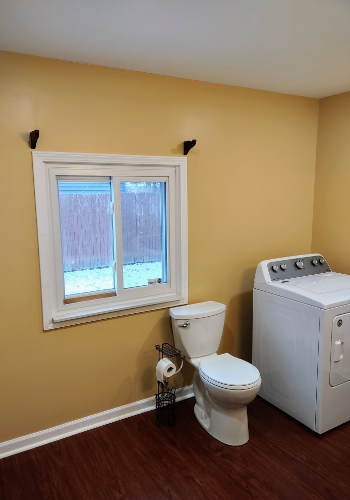 Klassisk inredning av ett mellanstort beige linjärt beige grovkök med garderob, med en integrerad diskho, luckor med infälld panel, skåp i mörkt trä, laminatbänkskiva, orange väggar, laminatgolv och brunt golv